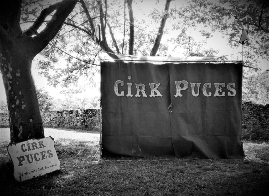 Une vue générale du mini-chapiteau de Cirk Puces avec son rideau et la pancarte indiquant : Cirk Puces lé plou péti Cirk dou monde